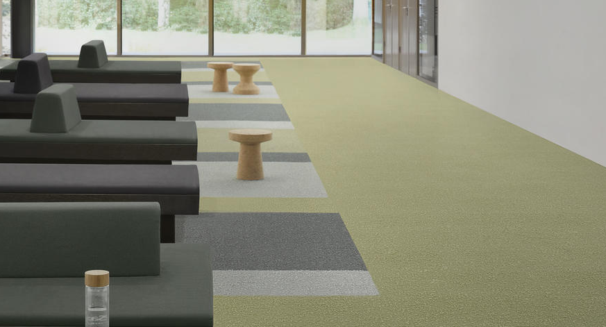 Une vue rapprochée d’une moquette de couleur verte avec des motifs géométriques gris en relief. Une vue rapprochée d'une moquette de couleur verte avec des motifs géométriques gris en relief.